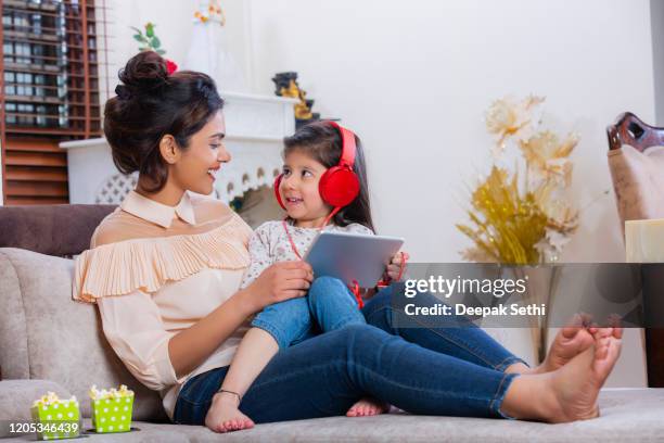 mother and daughter using digita table and listening to music stock photo - indian mother and child stock pictures, royalty-free photos & images