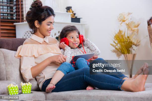 mother and daughter using digita table and listening to music stock photo - headphone girls stock pictures, royalty-free photos & images