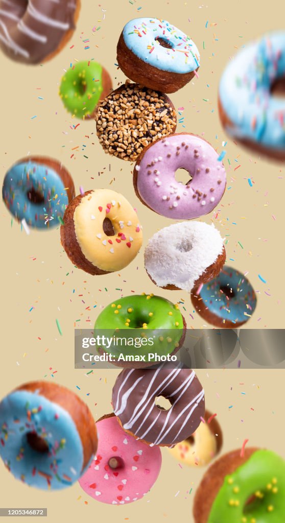 Bunte Donuts fliegen auf gelbem Hintergrund. Süßes Essen Hintergrund.