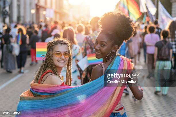 beautiful female couple at the love pride parade - pride stock pictures, royalty-free photos & images