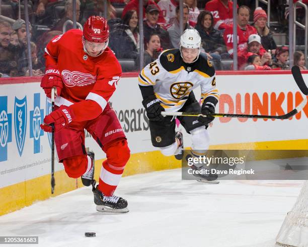 Christoffer Ehn of the Detroit Red Wings controls the puck in front of Danton Heinen of the Boston Bruins during an NHL game at Little Caesars Arena...