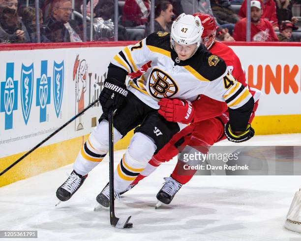 Torey Krug of the Boston Bruins skates around the net with the puck against the Detroit Red Wings during an NHL game at Little Caesars Arena on...