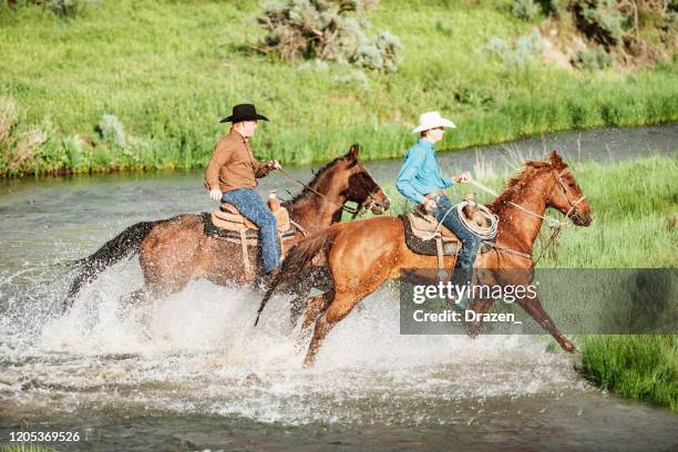 adult cowboys and cowgirls riding galloping horses - handsome cowboy stock pictures, royalty-free photos & images