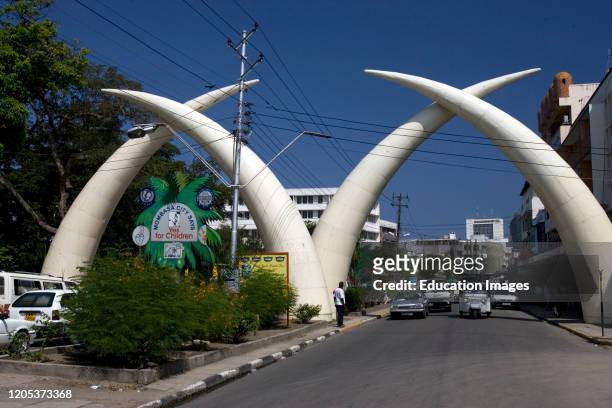 Road traffic passes elephant tusk road arch Mombasa Kenya.
