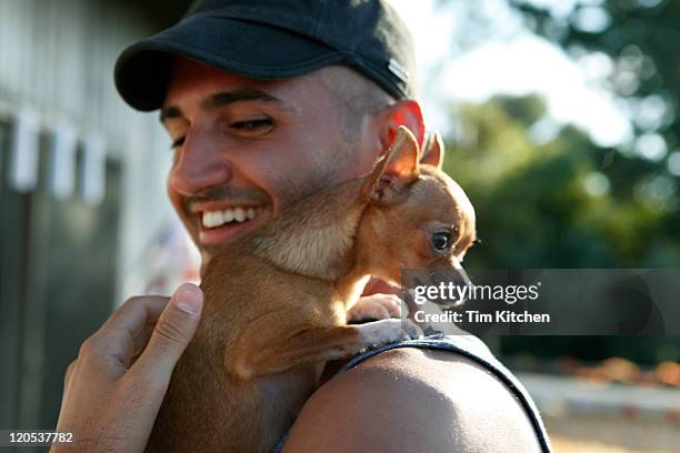 man with chihuaha on shoulder, smiling - hund klein stock-fotos und bilder