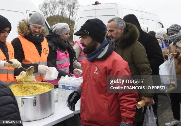 Refugee Shadi Abdulrahman , who graduated in tourism and law in Syria, distributes food in a migrant camp in Grande-Synthe, northern France, on...