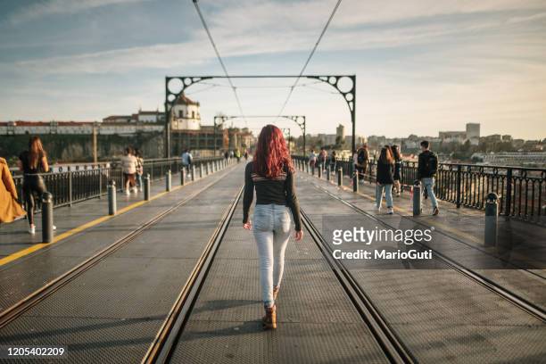 achtermening van jonge vrouw die in het midden van een straat loopt - rood gekleurd haar stockfoto's en -beelden
