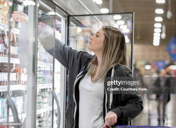 junge frau auswahl joghurt aus kühler in lebensmittelgeschäft - sportswear shopping stock-fotos und bilder