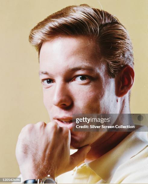 Richard Chamberlain, US actor, with his chin resting in his left hand in a studio portrait, against a yellow background, circa 1960.