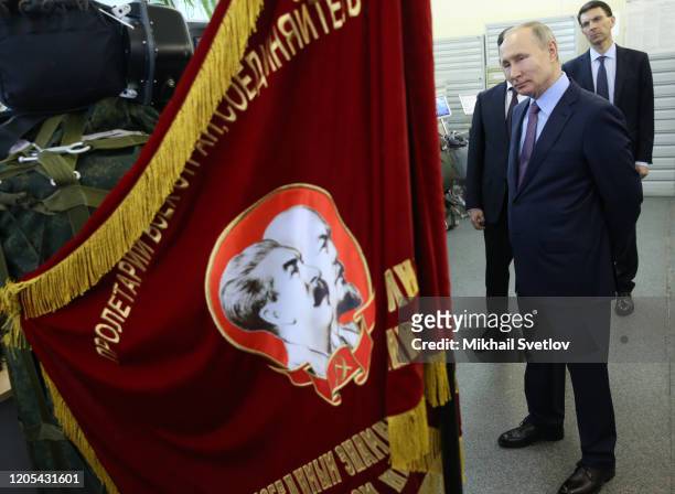 Russian President Vladimir Putin looks on the flag with portraits of Soviet leaders Vladimir Lenin and Joseph Stalin while visiting the Parachute...