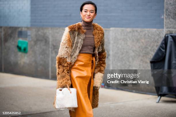 Olivia Lopze is seen wearing rust brown asymmetric skirt, faux fur coat, turtleneck, white bag outside Jonathan Simkhai during New York Fashion Week...