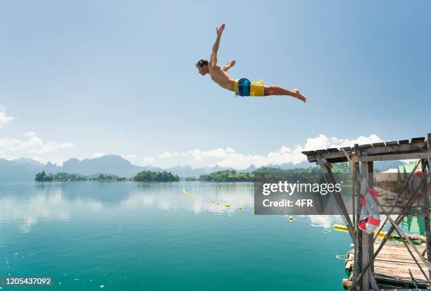 jumping in the clear lake ratchaprapha, khao sok nationalpark, thailand - springer stock-fotos und bilder