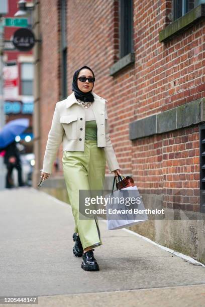 Guest wears sunglasses, a scarf over the head, a white jacket with buttons, a chain metallic necklace, a white and green top, green leather pants,...