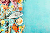 Seafood banner with a place for text. Fish, shrimps, crab, scallops, shot from above on a blue background with a place for text