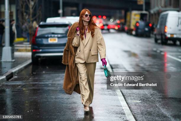 Guest wears sunglasses, a brown fluffy coat, a beige oversized jacket, a purple low neck top, flowing pants, pointy shoes, a green bag, purple...