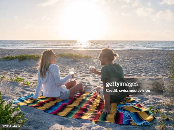 junges paar teilt ein glas wein bei sonnenuntergang am strand - cocoa beach stock-fotos und bilder