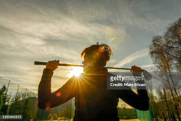 golfer leaning her golf club on her shoulders and with sunbeam - club de golf photos et images de collection