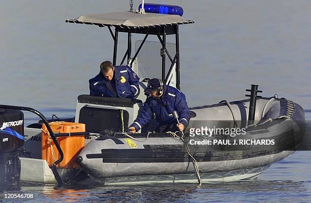 New York Police Department Scuba Team members Sgt. John Cummings and Detective Alan Kane adjust and listen to a "Ping Locater" 13 November 2001 as...