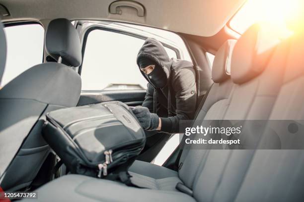 thief in a mask stealing backpack from the car - mugger stock pictures, royalty-free photos & images