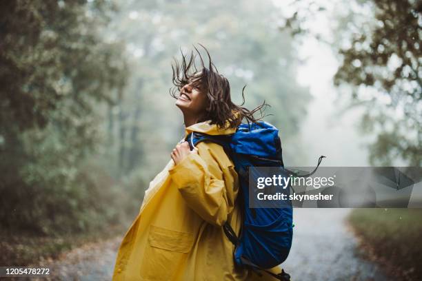 sorglose frau im regenmantel mit spaß in der natur. - raincoat stock-fotos und bilder