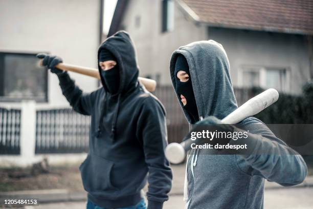 jeunes hommes retenant une batte de base-ball symbolisant le crime - gangster mask photos et images de collection