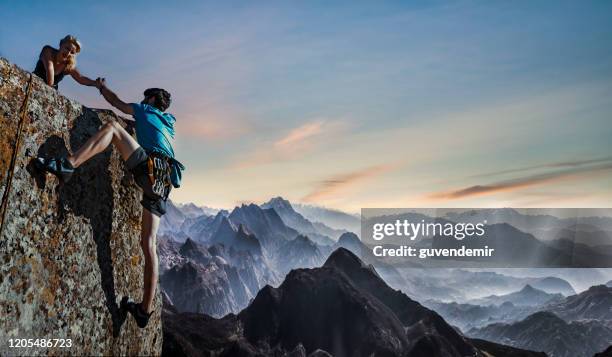 teamwork-paar helfende hand - climbing help stock-fotos und bilder