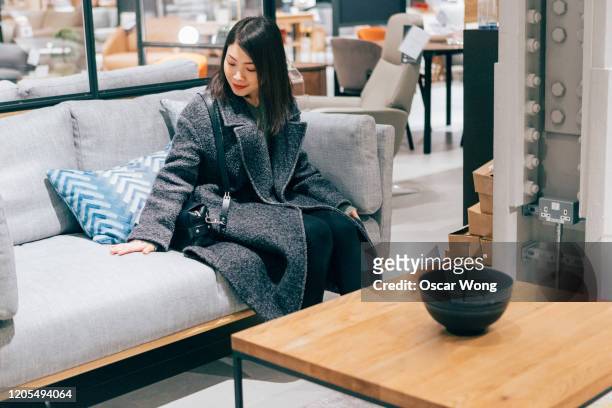 young woman at furniture store choosing sofa - furniture stock pictures, royalty-free photos & images