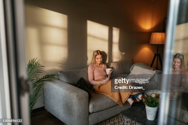 金髮碧眼的年輕女子在家裡使用手機 - scandinavian descent 個照片及圖片檔
