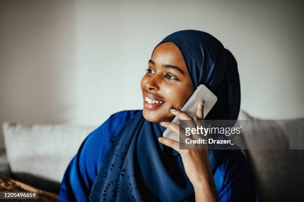 jonge vrouw van het midden-oosten met hijab die slimme telefoon gebruikt - eastern european woman stockfoto's en -beelden
