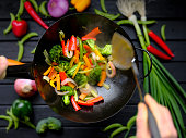 Stir frying and sauteing fresh colorful market vegetables in a hot wok.