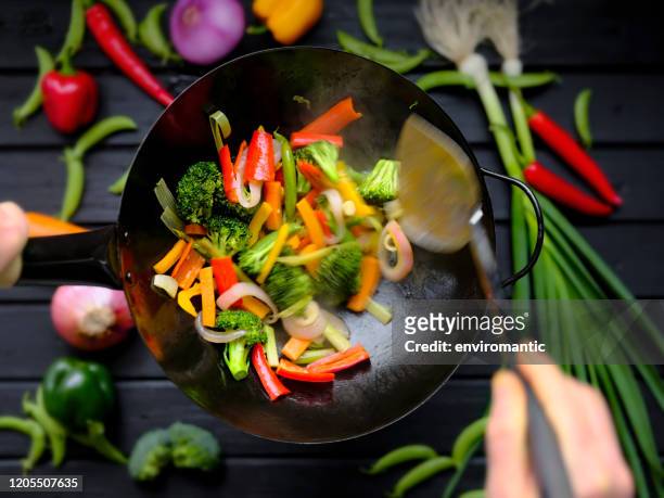 stir frying and sauteing fresh colorful market vegetables in a hot wok. - salteado imagens e fotografias de stock