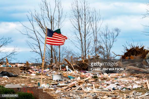 Flag flaps in the wind as US President Donald Trump tours tornado damage in Cookeville, Tennessee on March 6, 2020. - At least 24 are dead in the...