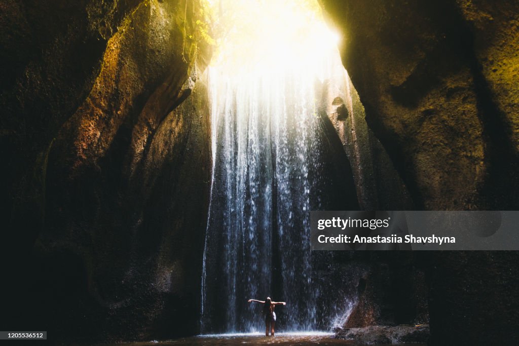 La donna incontra l'alba nella grotta sotto la grande cascata sull'isola di Bali, indonesia
