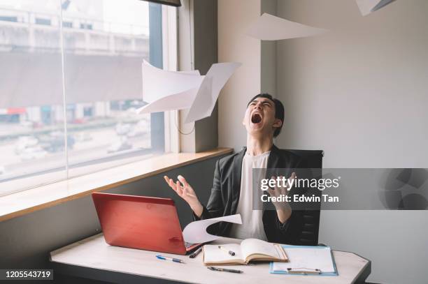 ein asiatischer chinesischer junger angestellter, der frustriert und emotionaler stress in seinem büro auf seinem stuhl sitzt - chef schreit stock-fotos und bilder