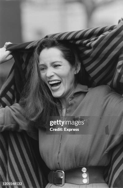 Nicaraguan American actress Barbara Carrera laughing as she holds a striped shawl up behind her head during a photo call to promote promote her...