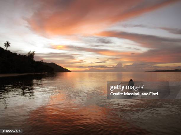 silhouette of a fisherman boat and kri island on the sunset reflected on the sea - yellow sea stock-fotos und bilder