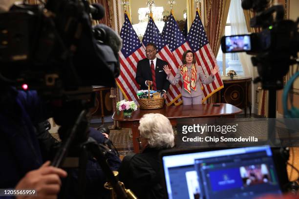 Journalists look on as Speaker of the House Nancy Pelosi presents Rep. Emanuel Cleaver with a basket with items from the San Francisco area,...
