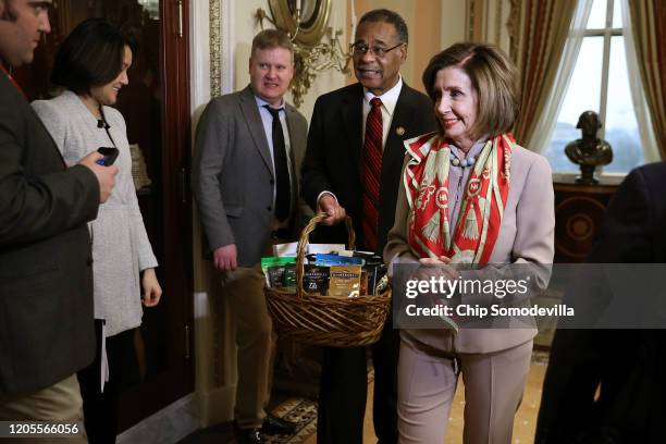 Journalists look on as Speaker of the House Nancy Pelosi presents Rep. Emanuel Cleaver with a basket with items from the San Francisco area,...