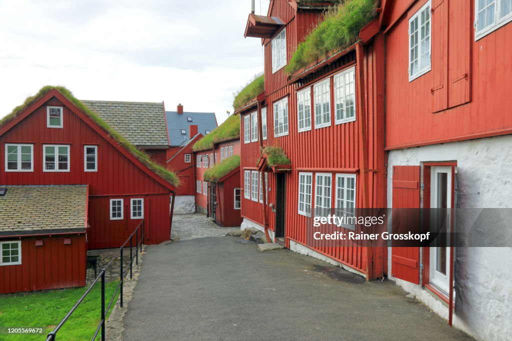 A cobblestone road through old wooden red buildings in the historic part of Tórshavn