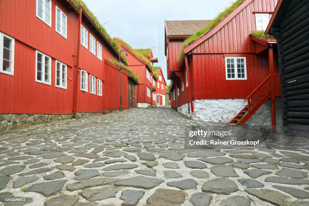 A cobblestone road through old wooden red buildings in the historic part of Tórshavn