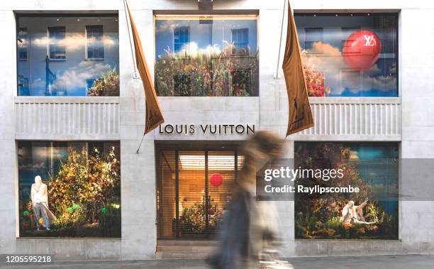 woman walking past the famous luxury retail store of lous vuitton in new bond street, mayfair, london. - louis vuitton flagship store in london stock pictures, royalty-free photos & images