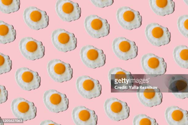 repeated fried eggs on the pink background - food styling stock-fotos und bilder
