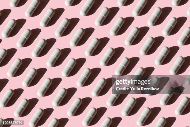 repeated pills on pink background - antibiotikaresistent stock-fotos und bilder