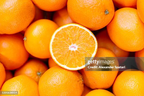 half of orange on the heap of oranges - orange fruit stock-fotos und bilder