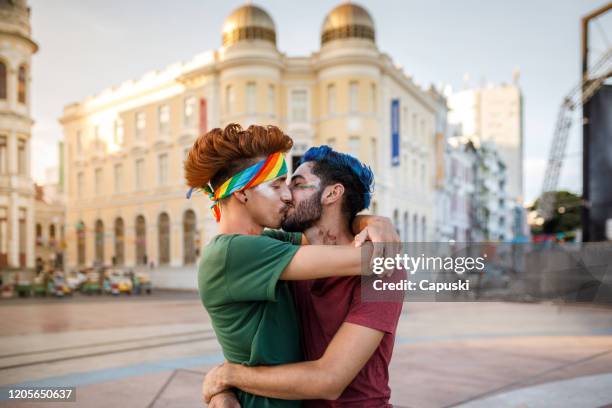 schwules paar küssen auf der straße bei karneval - gay kiss stock-fotos und bilder