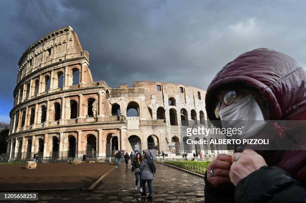 Man wearing a protective mask passes by the Coliseum in Rome on March 7, 2020 amid fear of Covid-19 epidemic. - Italy on March 6, 2020 reported 49...
