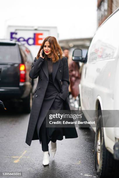 Christine Centenera wears a black long coat, a black mesh top, a skirt, white pointy shoes, outside Coach, during New York Fashion Week Fall Winter...