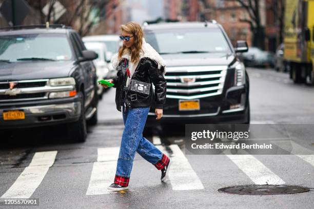 Guest wears sunglasses, a black leather jacket with white wool inner lining, a Vuitton rectangular rigid monogram clutch, blue denim pants with red...