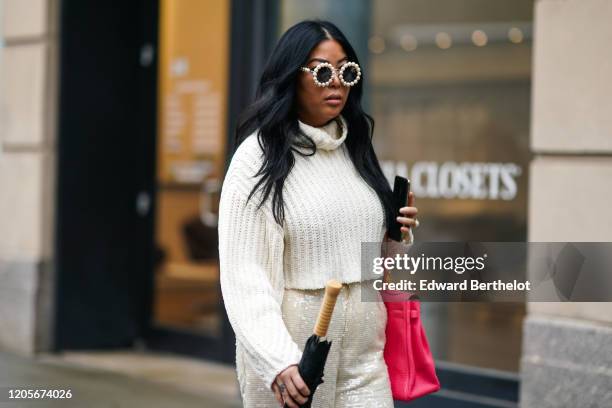 Guest wears pearl beaded circular sunglasses, a white wool pullover, a pink bag, during New York Fashion Week Fall Winter 2020, on February 11, 2020...