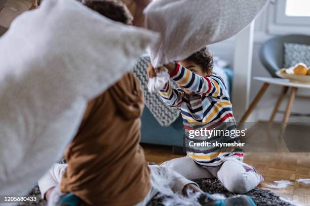 playful african american kids having fun during pillow fight at home. - sibling fight stock pictures, royalty-free photos & images